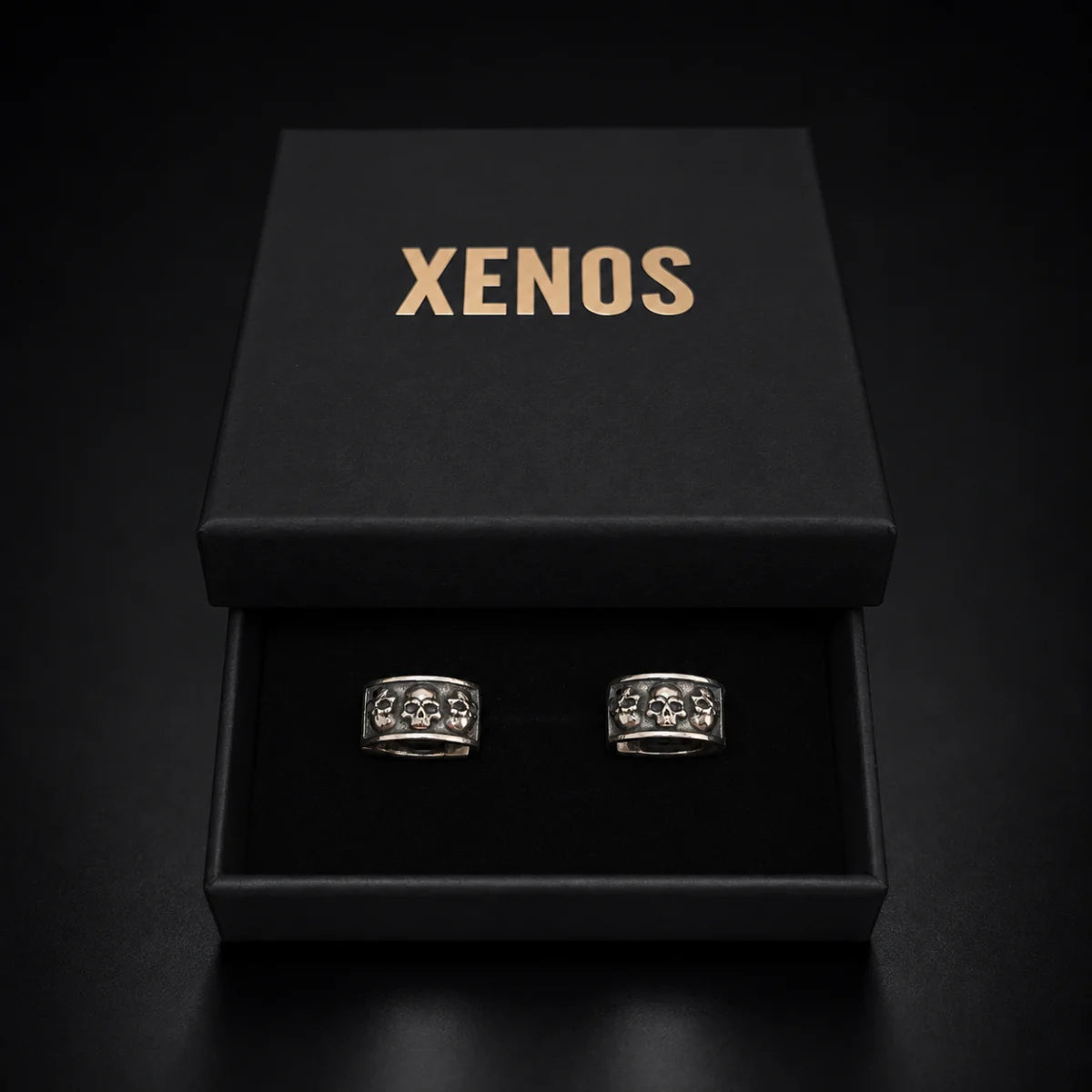 Men's Silver Skull Huggie Hoop Earrings Displayed in Xenos Jewelry Box