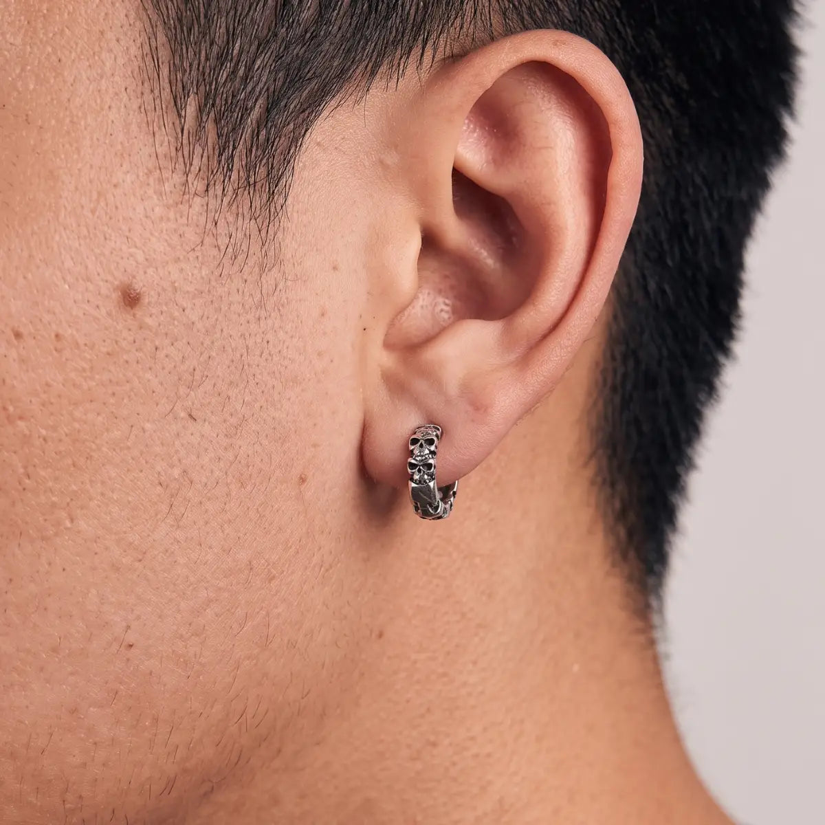 Multi Skull Head Huggie Earrings Silver Worn by Male Model Close Up