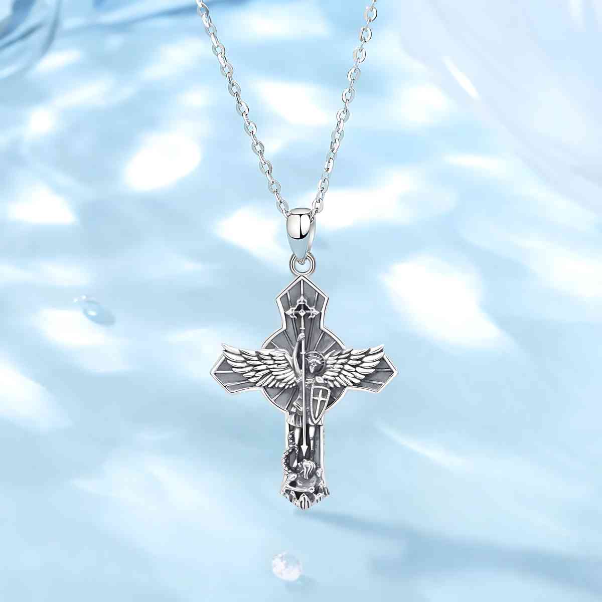 Saint Michael Cross Wings Necklace Displayed on Blue Surface Xenos Jewelry