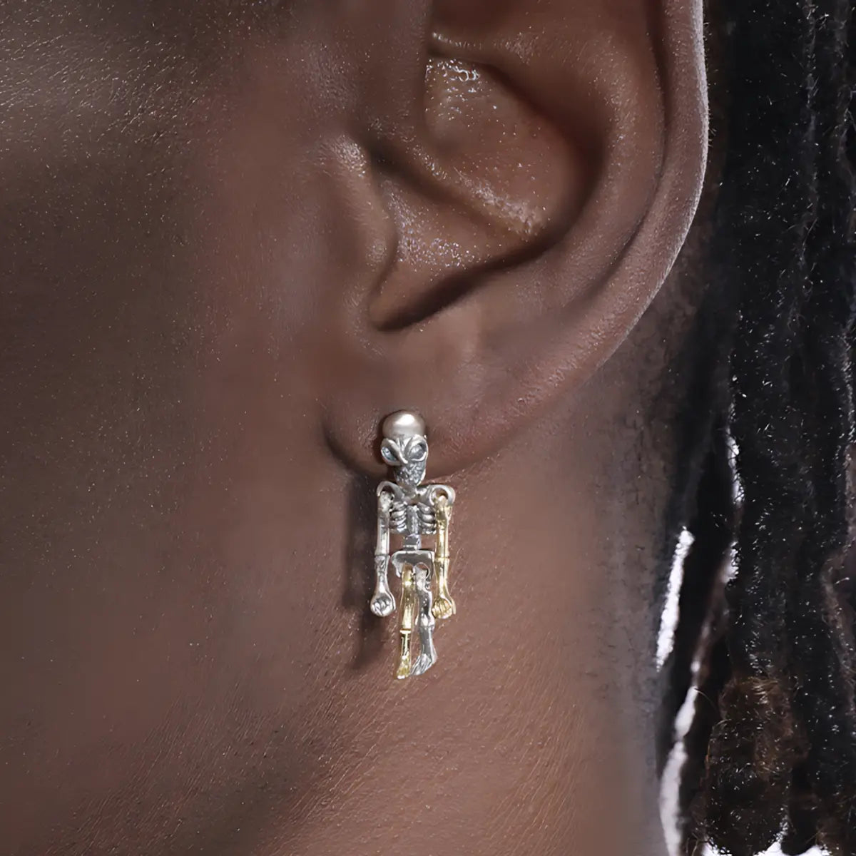 Skeleton dangle earrings sterling silver worn by male model close up