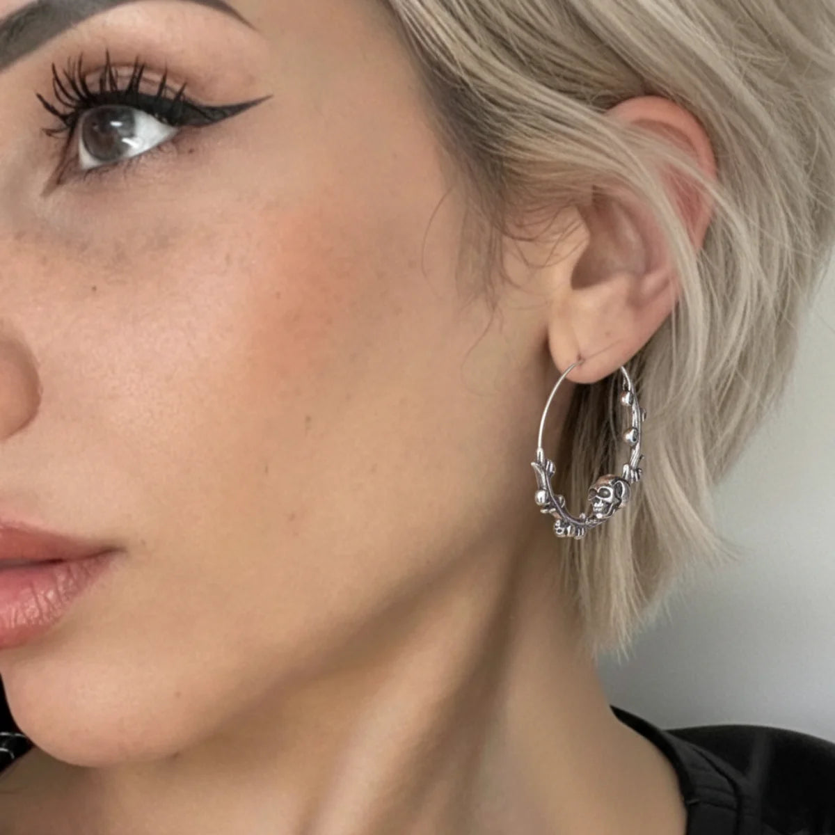 Steel Skulls on Branch Hoop Earrings Worn by Female Model Front Close Up