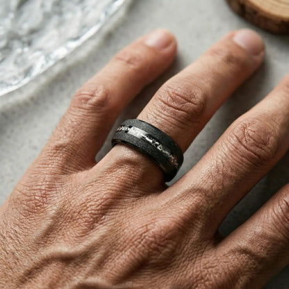 Top view of male model with hand flat on wooden surface wearing Black Meteorite Tungsten Ring