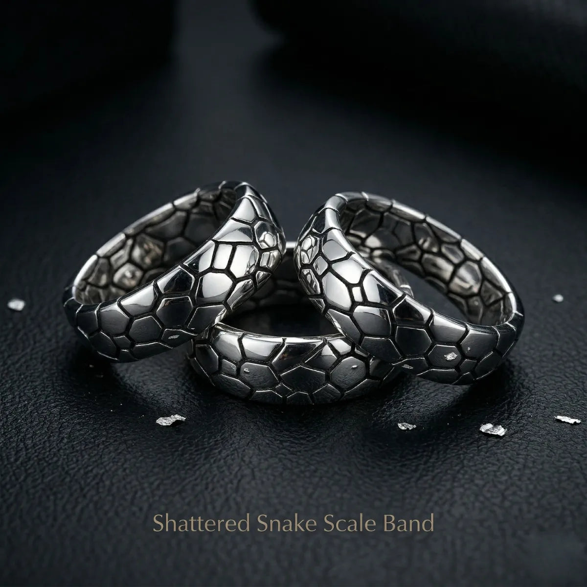 Collection of silver Shattered Snake Scale Bands on dark surface