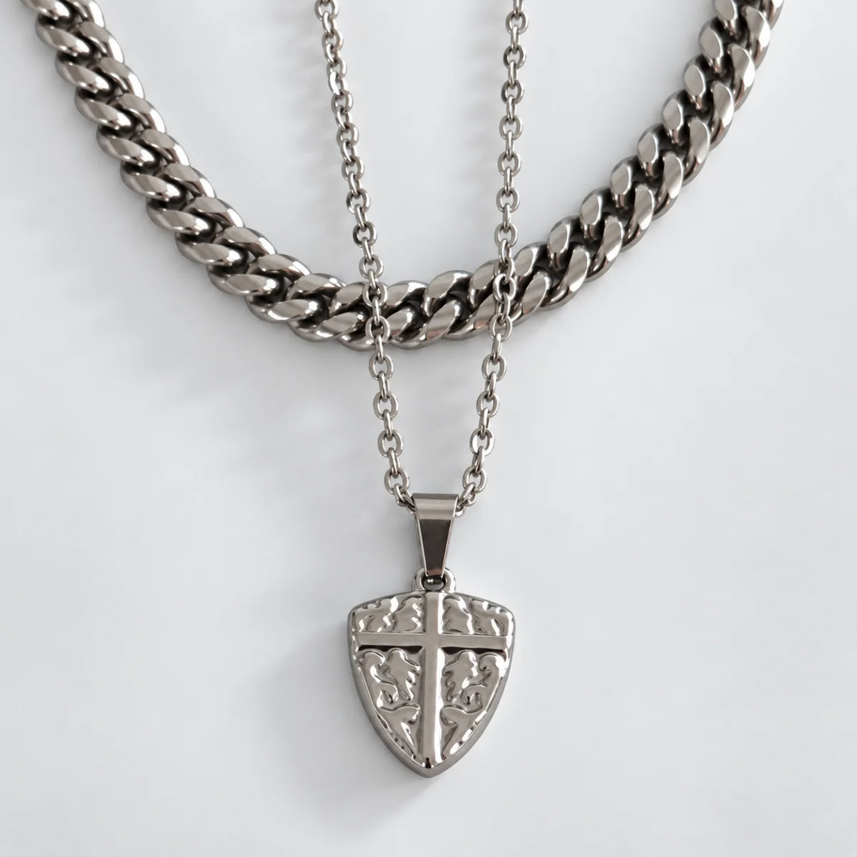 shield cross pendant necklace silver layered set white background