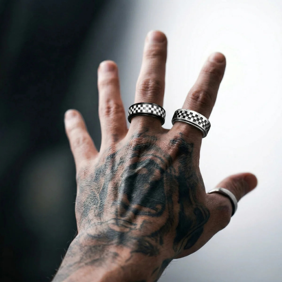 Tattooed hand wearing black and silver Checkered Spinner Bands